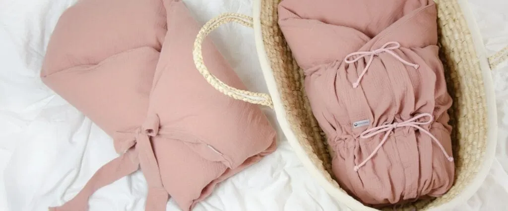 Světle starorůžová mušelínová zavinovačka sleepsheep v proutěném košíku
